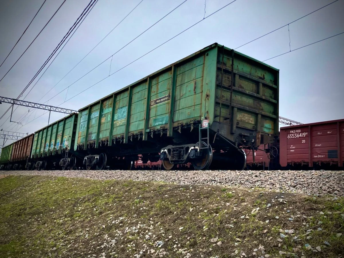 Зелені вантажні вагони на залізничних коліях під лініями електропередач